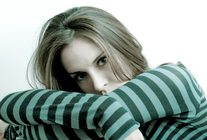 Afbeelding van depressieve vrouw die vermoeid over armen leunt en camera inkijkt bij artikel over psychische klachten overgang