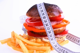Afbeelding van hamburger en patat met meetlint er om heen bij artikel over cholesterolgehalte