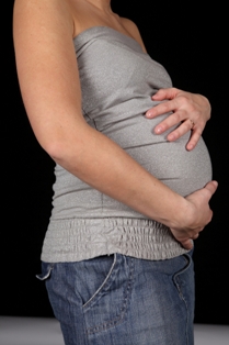 Afbeelding van zwangere vrouw met haar handen op haar buik bij artikel snel fit na bevalling