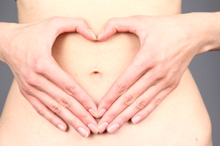 Afbeelding van vrouwenbuik die met haar handen een hart maakt op haar buik bij artikel roken tijdens zwangerschap